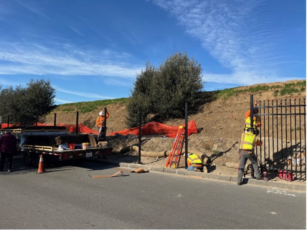 Workers installing steel fence along the slope