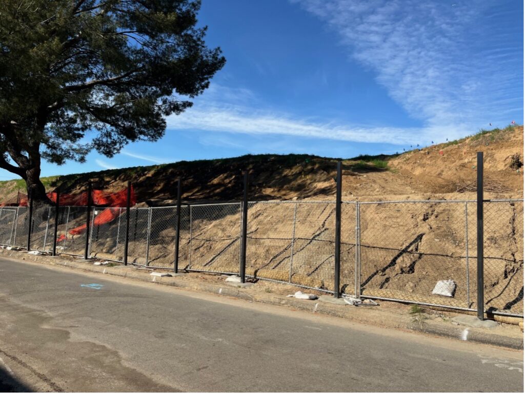 Slope with steel pole installed and chainlink fence behind