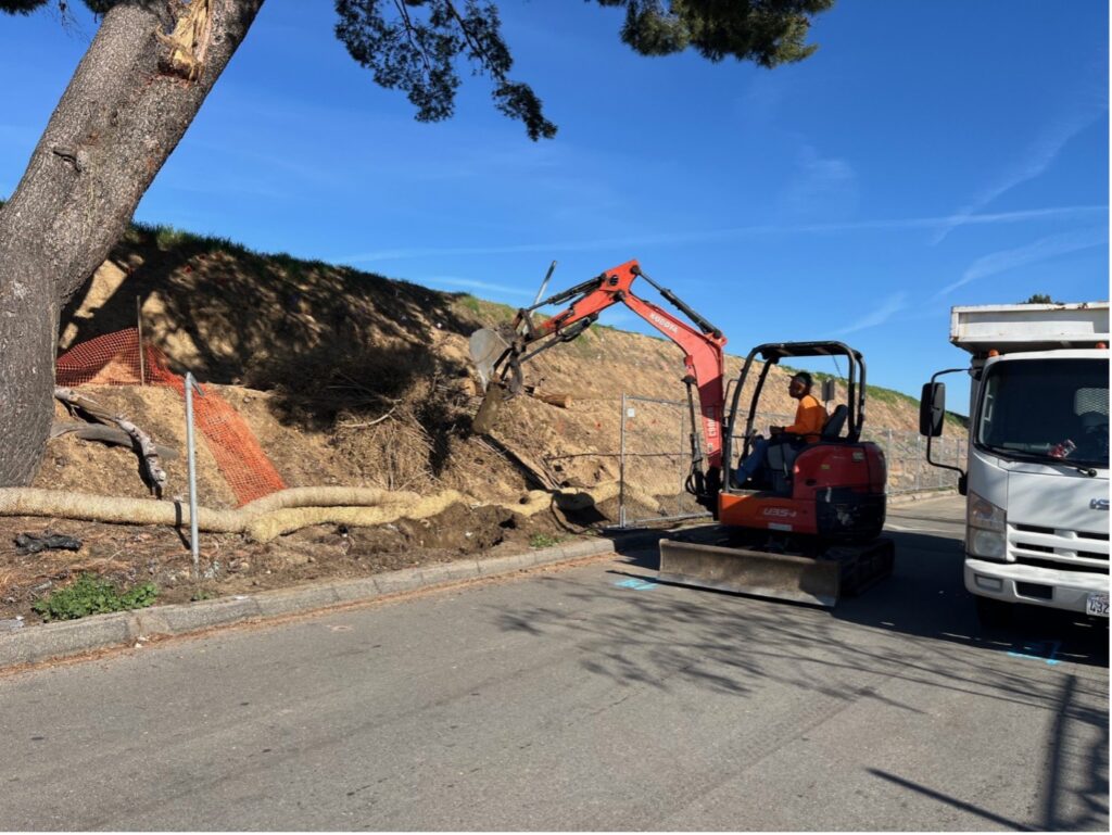 Worker with backhole digging into slope