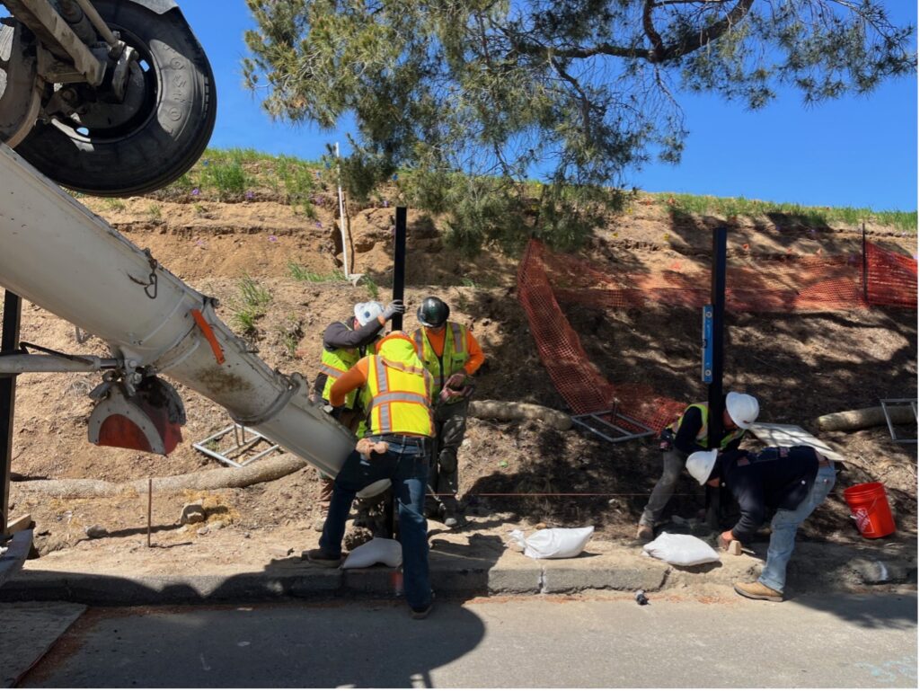 Workers pouring concrete to steel polls along the curve