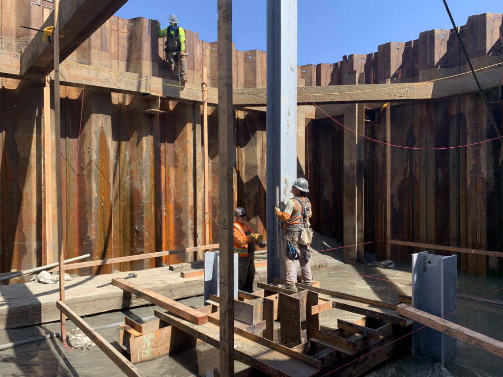 Workers inspecting the beam for vertical alignment at a construction site
