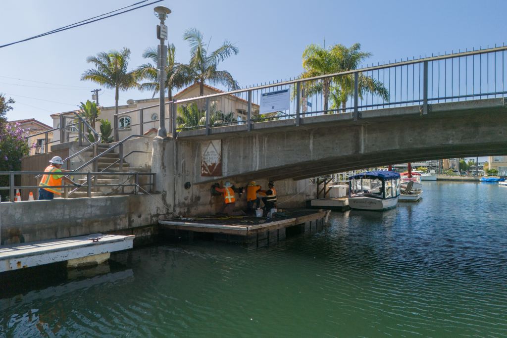 Alamitos Bay - workers under a bridge working from a platform - angle view